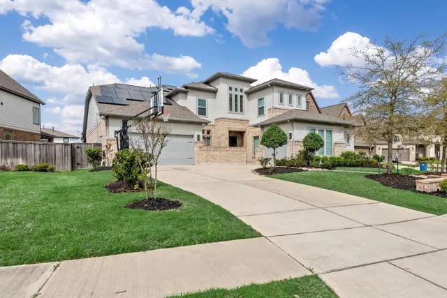 a front view of a house with a garden and a tree