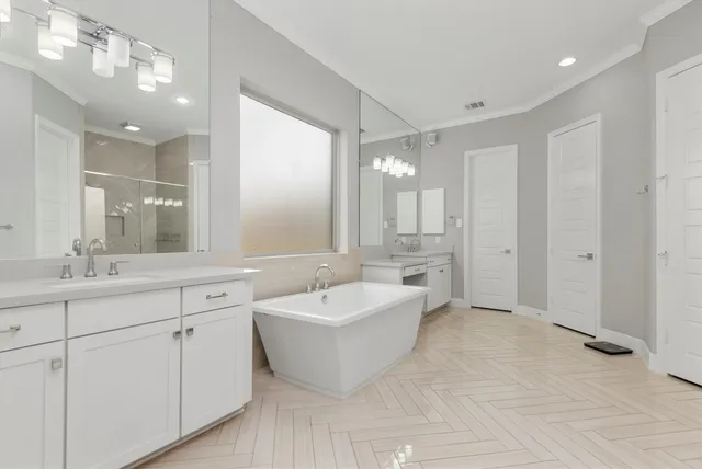 a spacious bathroom with a double vanity sink mirror and bathtub