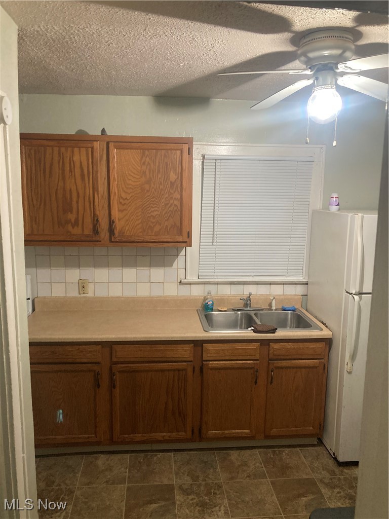 851 Springdale Street Akron, OH 44310 - Photo 10 of 22 Kitchen with a textured ceiling, tasteful backsplash, sink, fridge, and ceiling fan