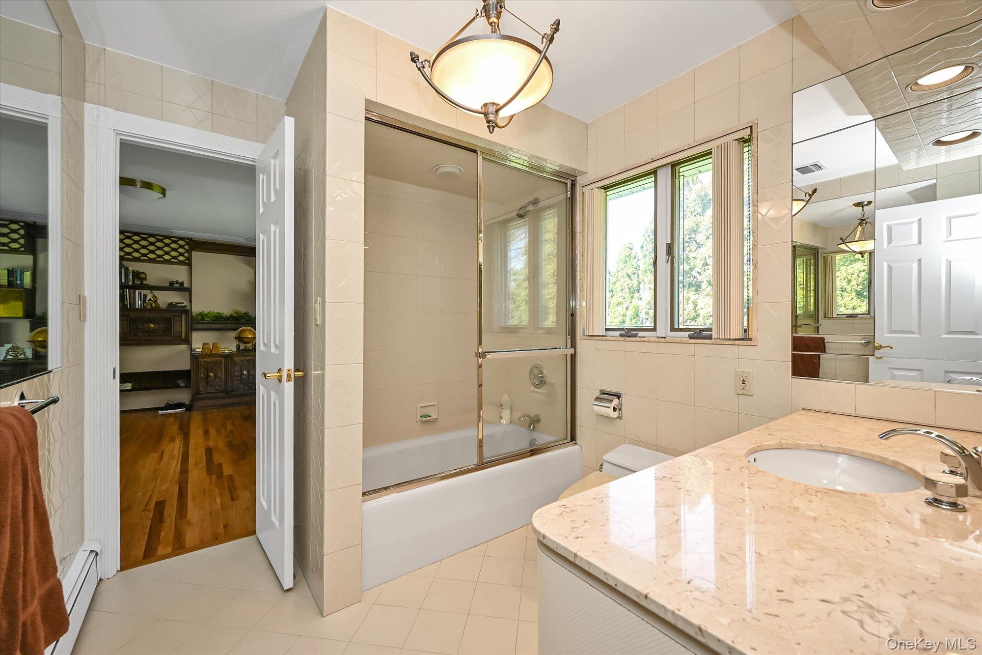 85 Meadow Woods Road Great Neck, NY 11020 - Photo 17 of 25 This shared full bathroom connects the 2nd and 3rd bedrooms, featuring a ceramic tile floor and a granite countertop.