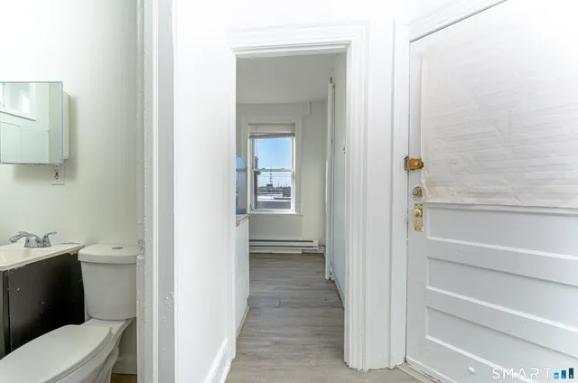 a view of an empty room with wooden floor and a window