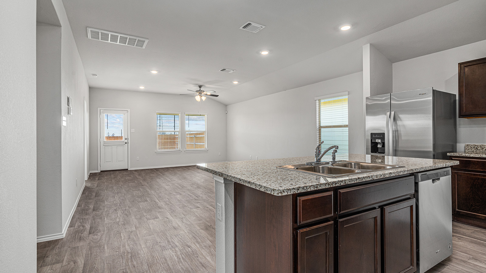 1303 Coriander Road Temple, TX 76501 - Photo 3 of 20 Kitchen island with a double basin sink and granite countertop, stainless steel appliances, dark wood-finish cabinetry, recessed lighting, and wood-finish flooring