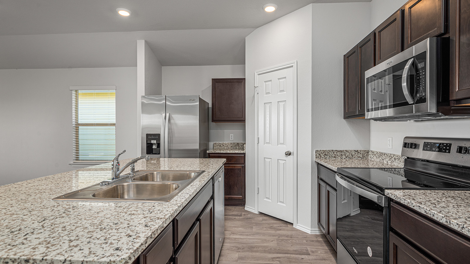 1303 Coriander Road Temple, TX 76501 - Photo 4 of 20 Spacious kitchen featuring a large island with an undermount double-basin sink, granite countertops, and dark wood cabinetry