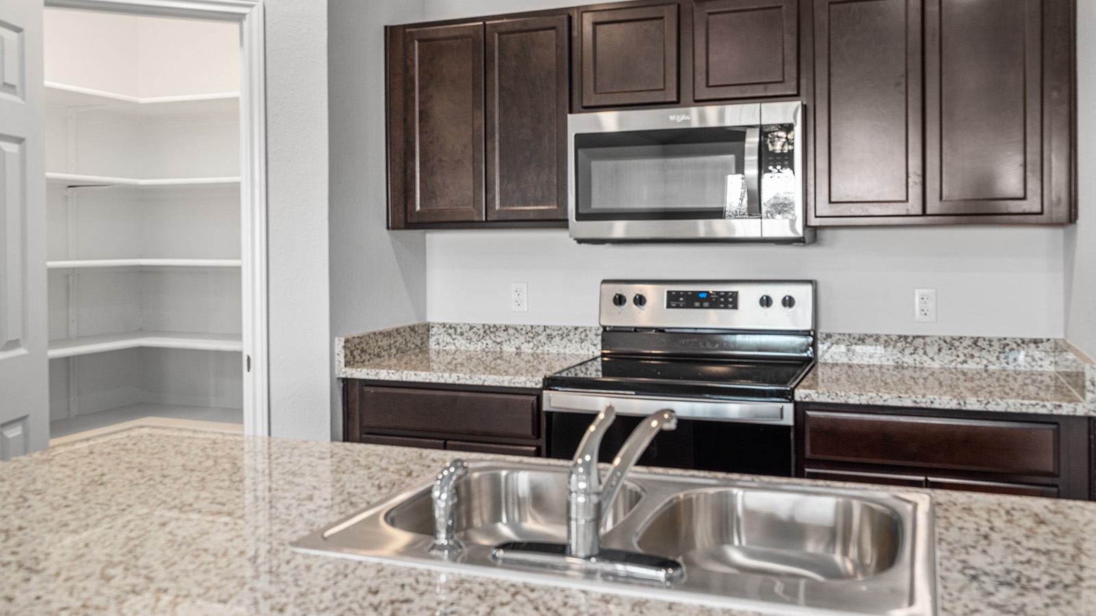 1303 Coriander Road Temple, TX 76501 - Photo 5 of 20 Kitchen featuring granite-style countertops, dark wood-finish cabinetry, stainless steel appliances, and a built-in pantry with shelving