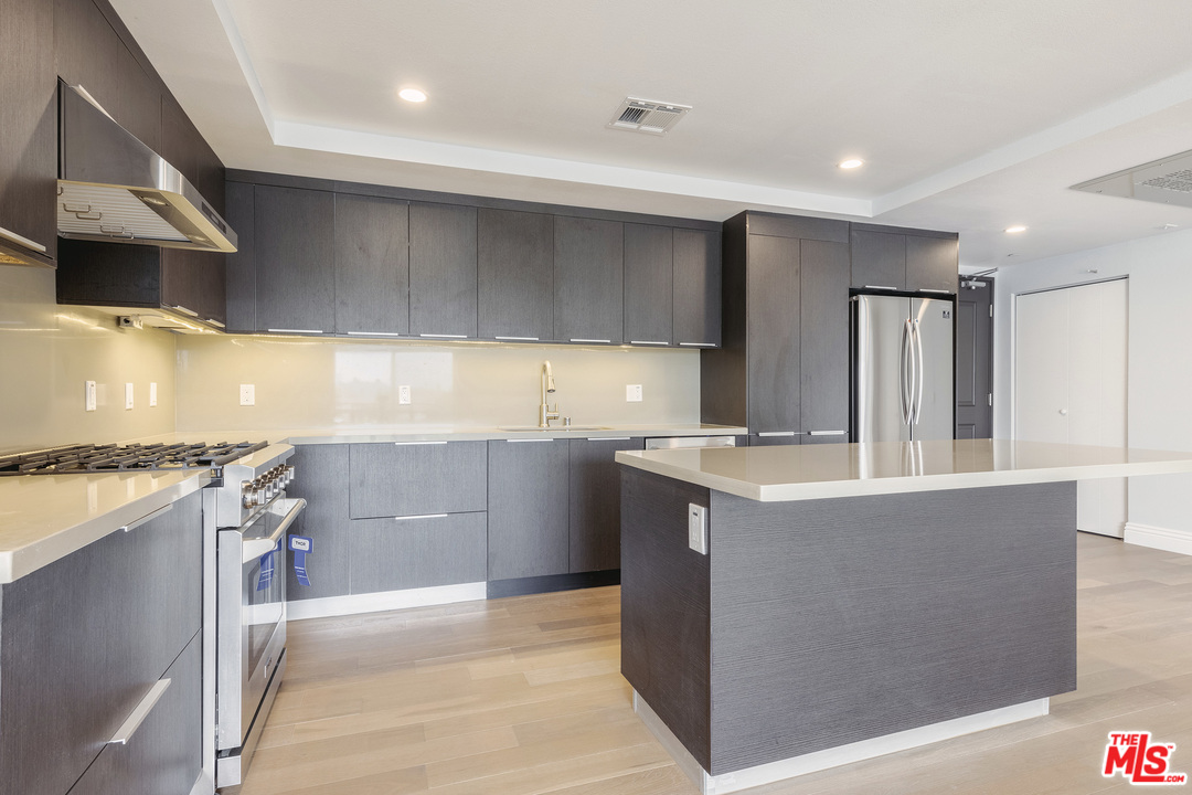 a kitchen with kitchen island a counter top space a sink stainless steel appliances and cabinets