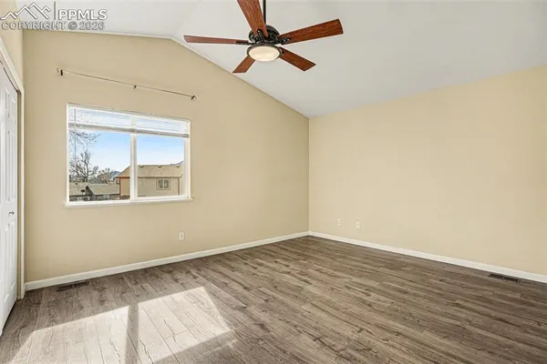 an empty room with wooden floor and windows