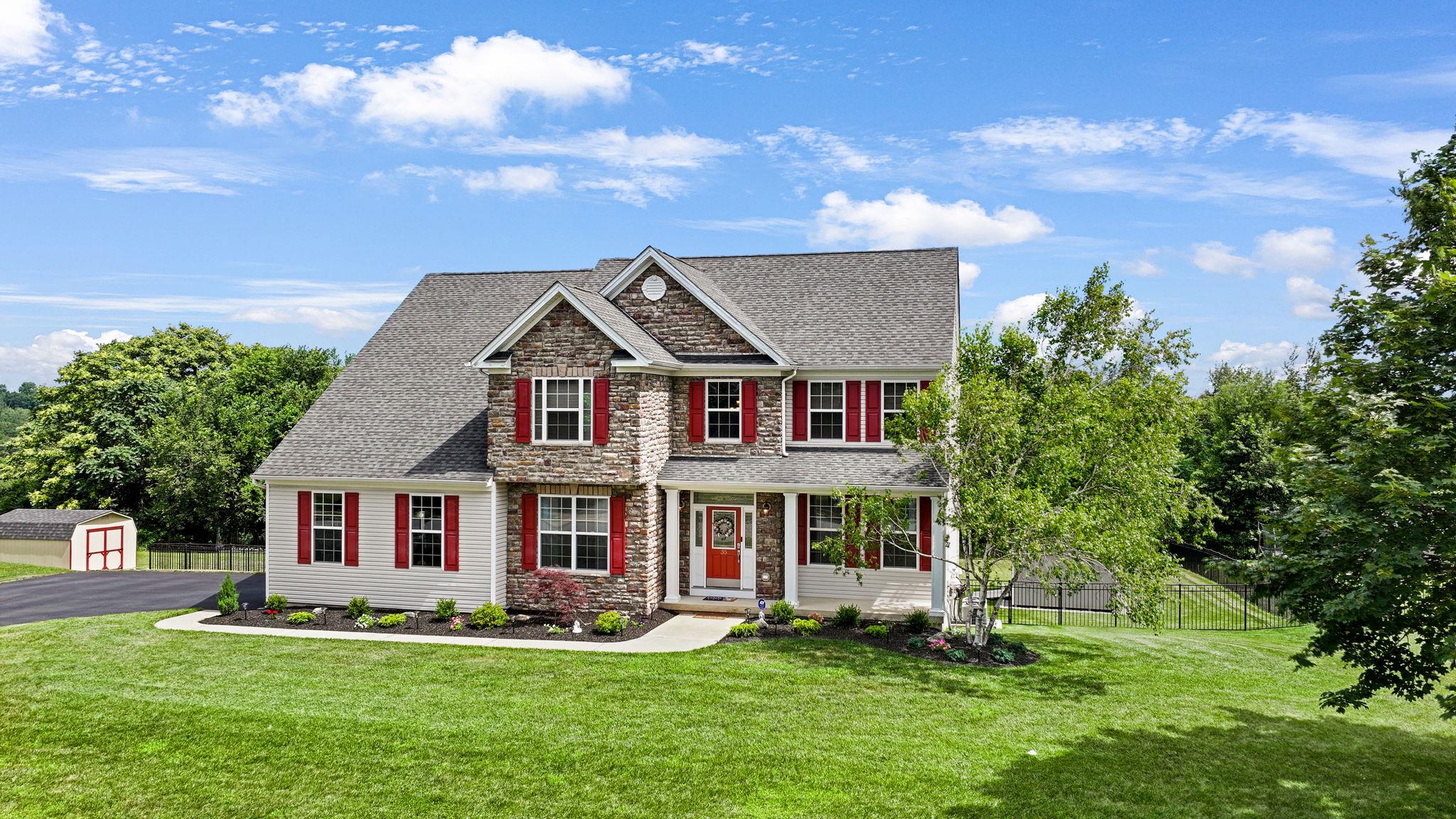 a front view of a house with a garden and trees