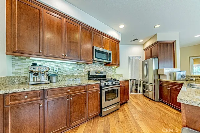 a kitchen with granite countertop stainless steel appliances wooden cabinets a stove top oven