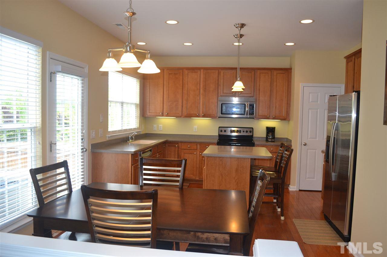 5423 Shaker Heights Lane Raleigh, NC 27613 - Photo 11 of 24 a kitchen with stainless steel appliances granite countertop a stove top oven a refrigerator and a dining table with wooden floor
