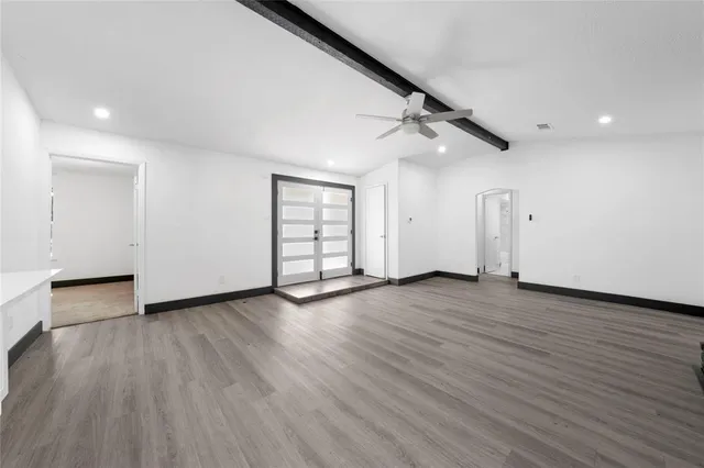 an empty room with wooden floor door and windows