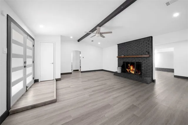 an empty room with wooden floor fireplace and windows