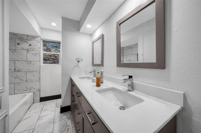 a bathroom with a sink a tub and a mirror