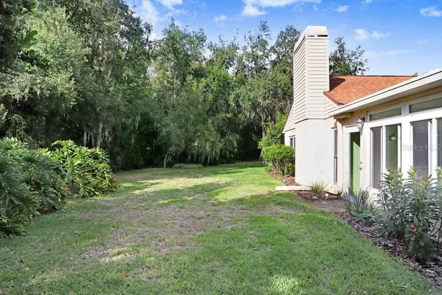 a backyard of a house with plants and large trees