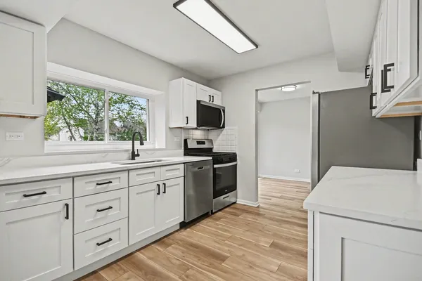 a kitchen with white cabinets and a wooden floor