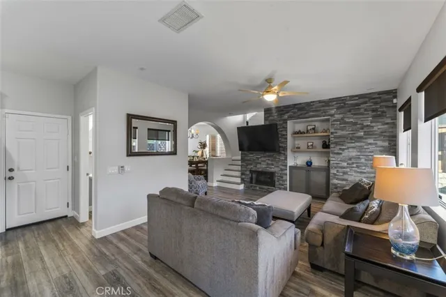 a living room with furniture a ceiling fan and a flat screen tv