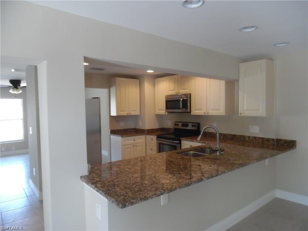 3055 52nd Street Southwest Naples, FL 34116 - Photo 3 of 21 a kitchen with stainless steel appliances granite countertop a sink refrigerator and cabinets
