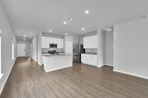 a view of kitchen with kitchen island stainless steel appliances refrigerator stove microwave and cabinets