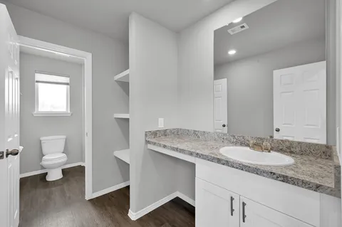 a bathroom with a granite countertop sink a toilet and a mirror