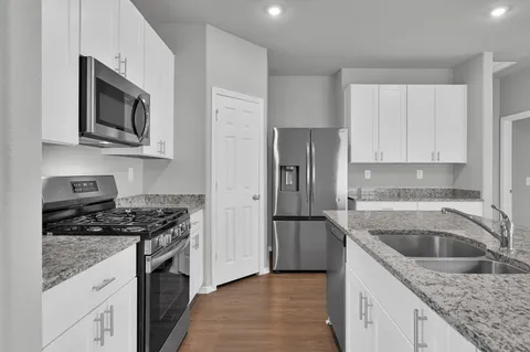 a kitchen with stainless steel appliances granite countertop a sink stove and microwave