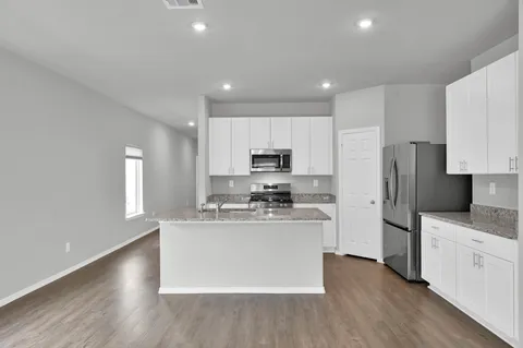 a kitchen with stainless steel appliances granite countertop a refrigerator a stove top oven a sink and dishwasher with wooden floor