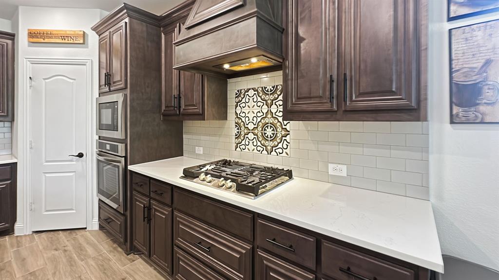 5216 Troupe Road McKinney, TX 75071 - Photo 12 of 40 Kitchen featuring rich wood cabinetry, stainless steel built-in appliances, a gas cooktop, light-toned countertops, and a decorative tile backsplash
