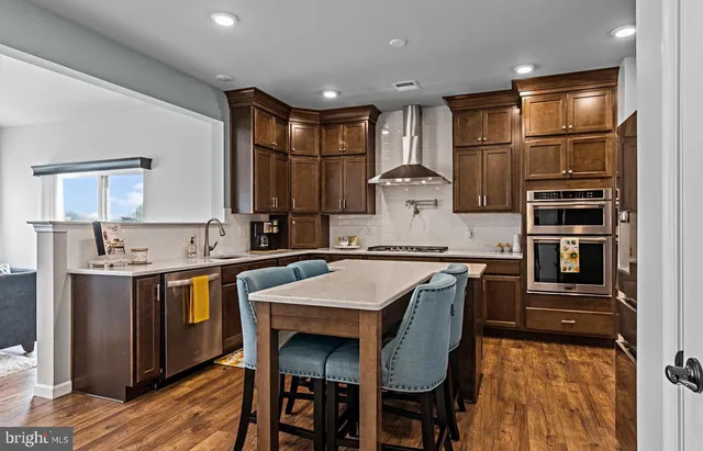 a kitchen with stainless steel appliances granite countertop a refrigerator a sink dishwasher a stove with wooden cabinets and floor