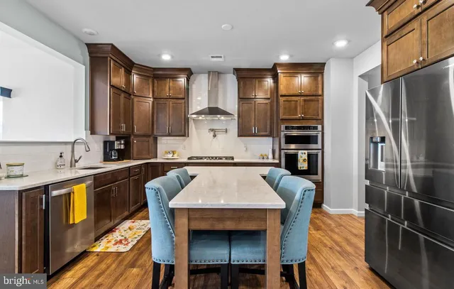 a kitchen with stainless steel appliances granite countertop a sink a stove a refrigerator cabinets and chairs