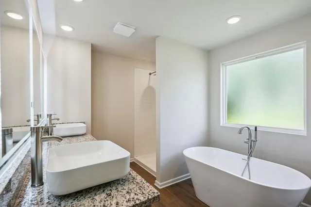 a bathroom with a white tub sink and mirror