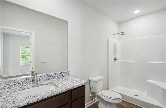 a bathroom with a granite countertop sink a toilet and shower