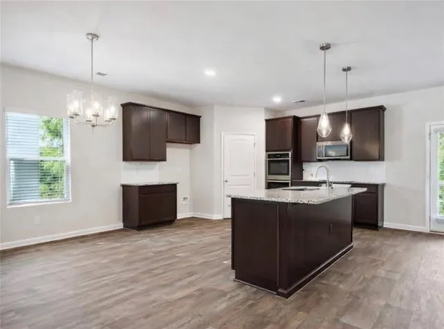 a kitchen with stainless steel appliances kitchen island granite countertop a stove and a wooden floor
