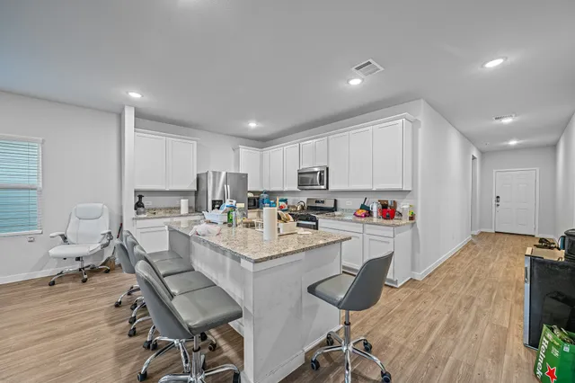 a large white kitchen with lots of counter space a sink appliances and cabinets