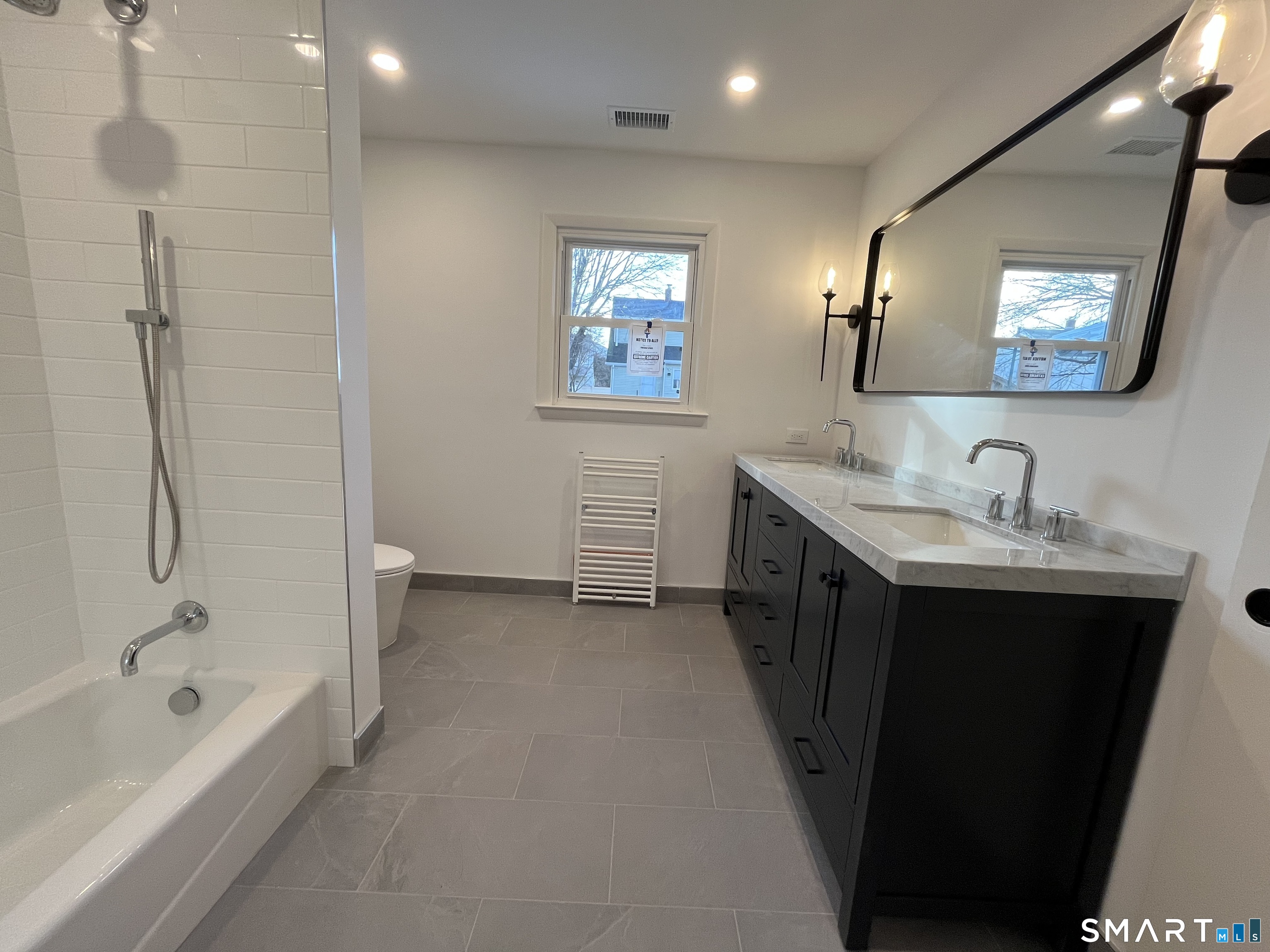 34 Keith Street, Unit 2 Stamford, CT 06902 - Photo 7 of 15 a bathroom with a double vanity sink a mirror a bathtub and shower