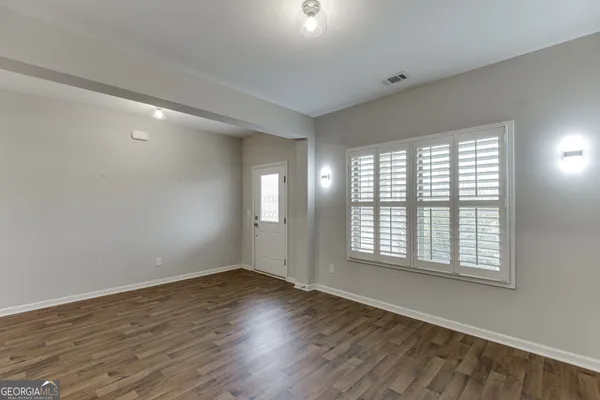 an empty room with wooden floor fireplace and windows