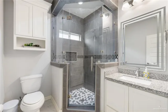 a bathroom with a granite countertop toilet sink and mirror
