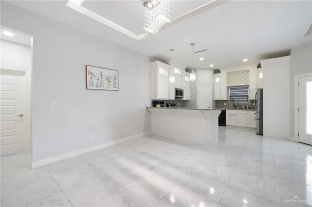 a large white kitchen with kitchen island a sink stainless steel appliances and cabinets