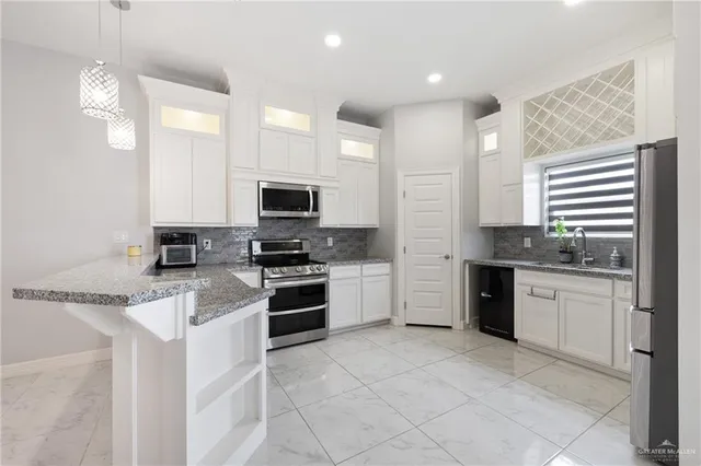 a kitchen with granite countertop a sink stainless steel appliances and cabinets