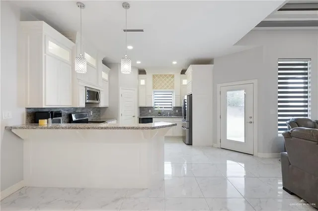 a large kitchen with stainless steel appliances a refrigerator a sink dishwasher with a dining table and chairs