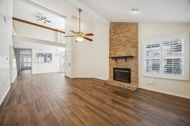 a view of a livingroom with wooden floor a fireplace and entryway