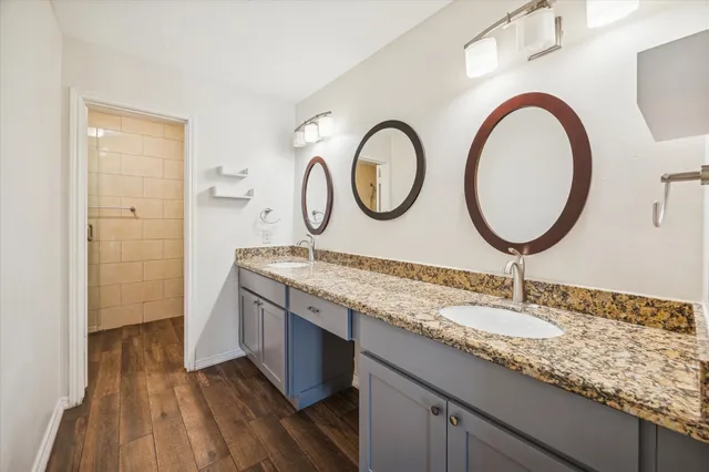 a bathroom with a granite countertop double vanity sink and a mirror