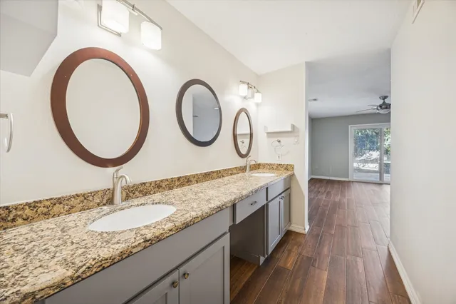 a bathroom with a granite countertop double vanity sink and a mirror