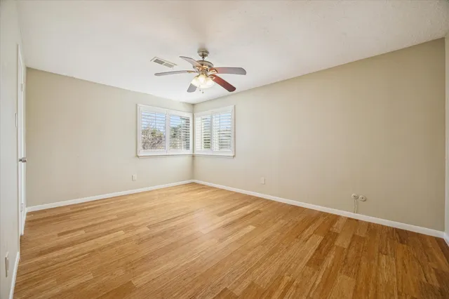 a view of an empty room with window and wooden floor