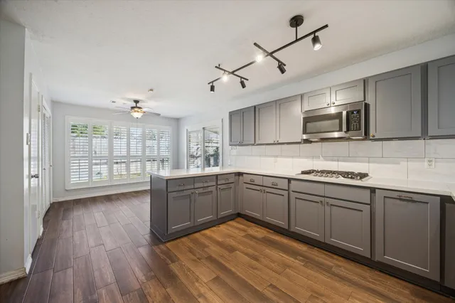 a kitchen with stainless steel appliances granite countertop a stove top oven a sink with wooden cabinets and glass door