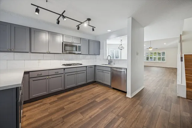 a kitchen with stainless steel appliances kitchen island granite countertop a sink cabinets and wooden floor