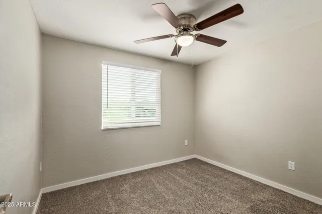 an empty room with a window and a fan
