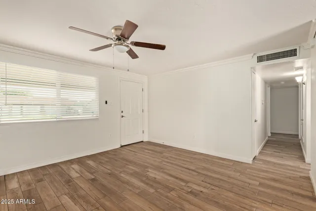 a view of empty room with wooden floor and fan