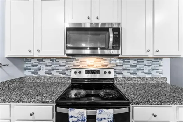 a view of kitchen with stainless steel appliances granite countertop a sink a counter top space and cabinets
