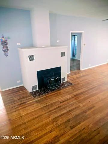 a view of empty room with wooden floor and fireplace