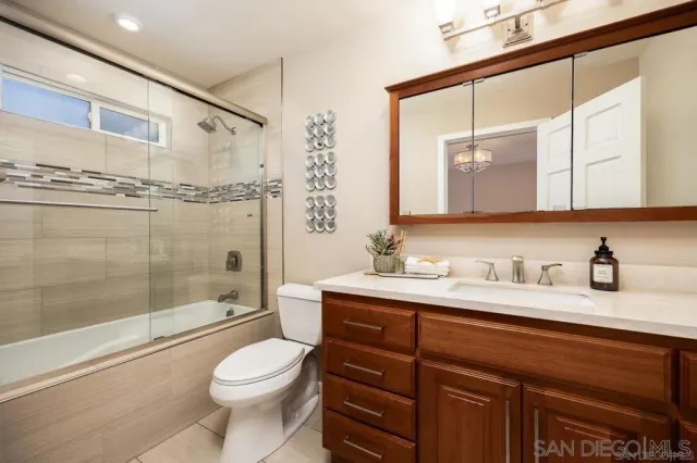 a bathroom with a granite countertop sink toilet mirror and shower