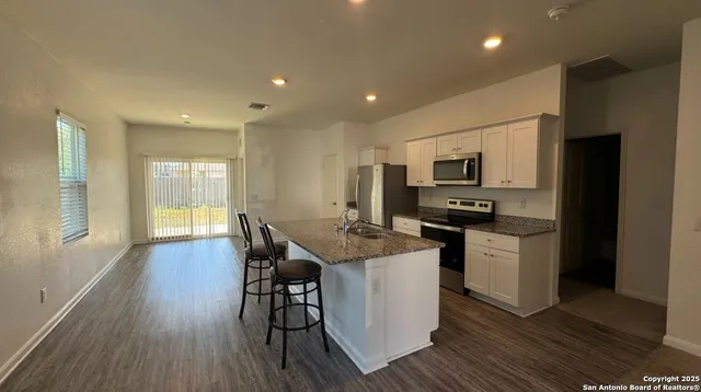 a kitchen with stainless steel appliances kitchen island granite countertop a stove a sink a refrigerator and a microwave