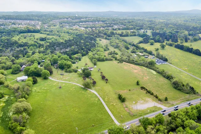 an aerial view of residential houses with outdoor space and trees